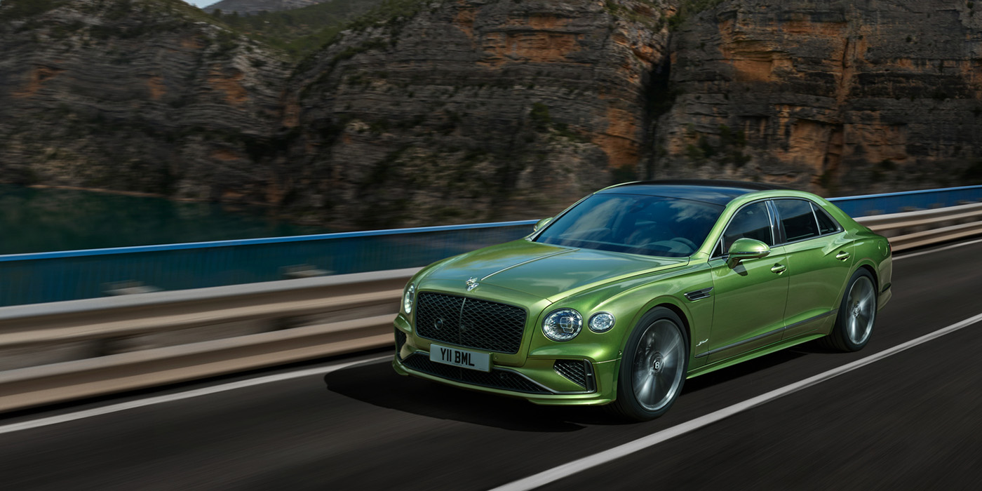 Bentley Valencia Bentley New Flying Spur Speed v8 hybrid sedan driving dynamically on a mountain road in Tourmaline Green paint