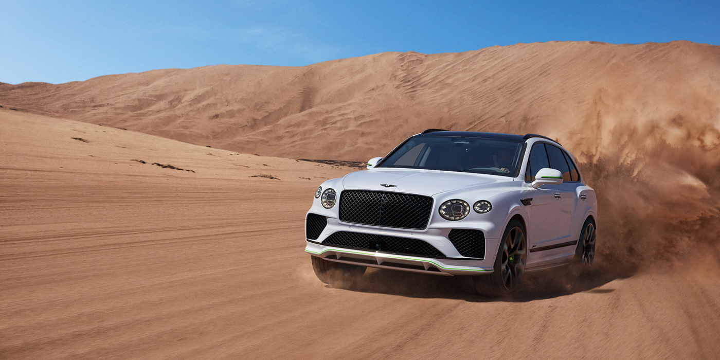 Bentley Valencia Bentley Bentayga Speed SUV front three quarter in Snow Quarts Pearlescent by Mulliner white paint driving dynamically through the desert