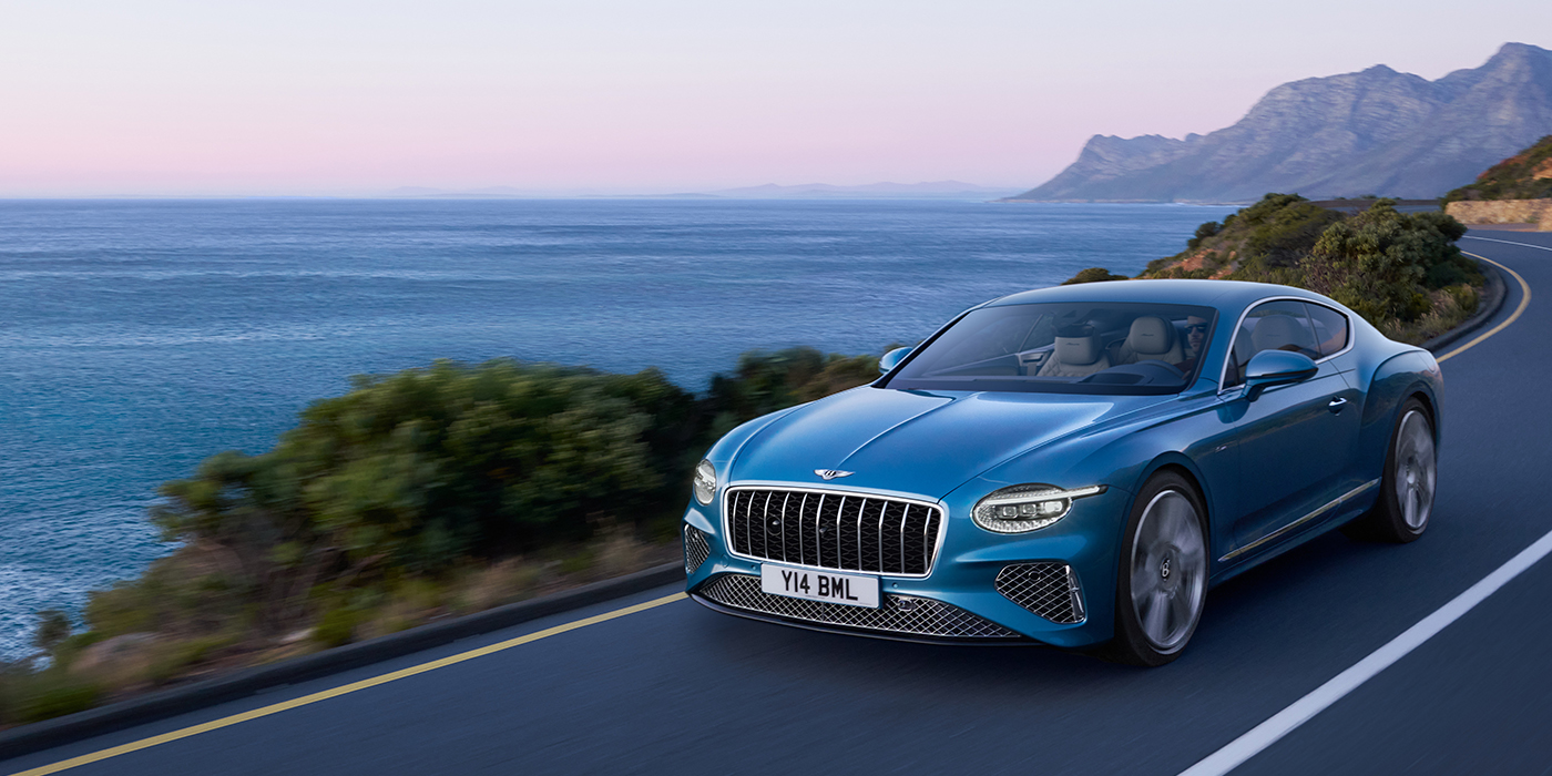 Bentley Valencia New Bentley Continental GT Azure coupe in Light Windsor blue paint with 22 inch Azure wheels and chrome grill, driving dynamically by the sea