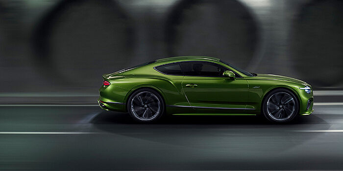  Bentley Valencia Bentley Continental GT coupe in Tourmaline Green paint driving in profile on a dark road