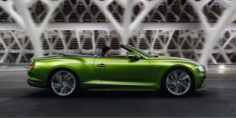 Bentley Valencia Bentley Continental GTC Speed convertible side profile in Tourmaline Green paint driving dynamically on a bridge at night