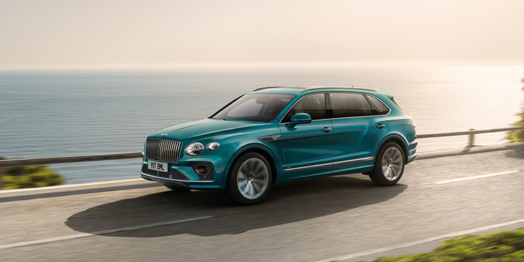 Bentley Valencia Bentley Bentayga Extended Wheelbase Azure SUV in Topaz blue paint driving dynamically by the ocean