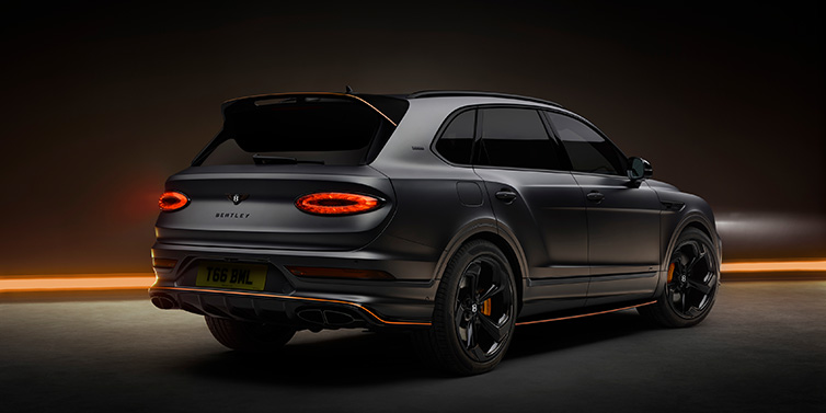 Bentley Valencia Bentley Bentayga S Black Edition SUV rear three quarter in Anthracite Satin paint against a dark red and yellow background