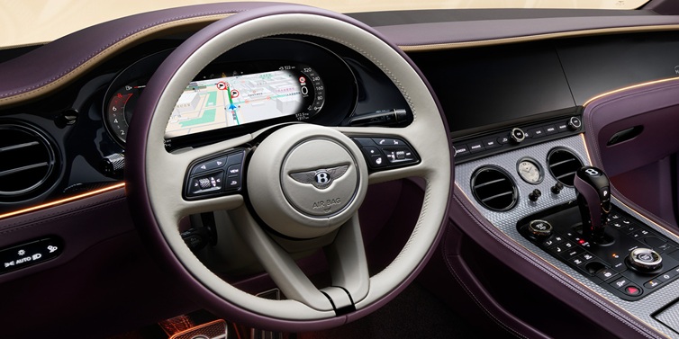 Bentley Valencia Bentley Continental GT Mulliner coupe front interior showing steering wheel and drivers screens surrounded by Linen and Damson hides and Grand Black veneer